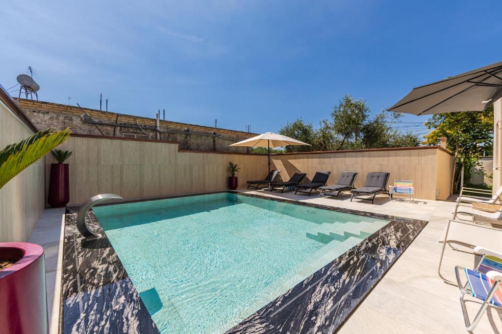 a swimming pool with chairs and an umbrella at Oasis Paradise Pool Villa in Durrës