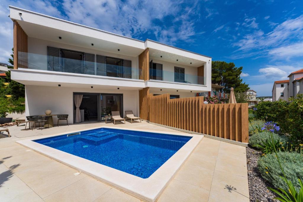 a villa with a swimming pool in front of a house at Villa Cvita west in Primošten