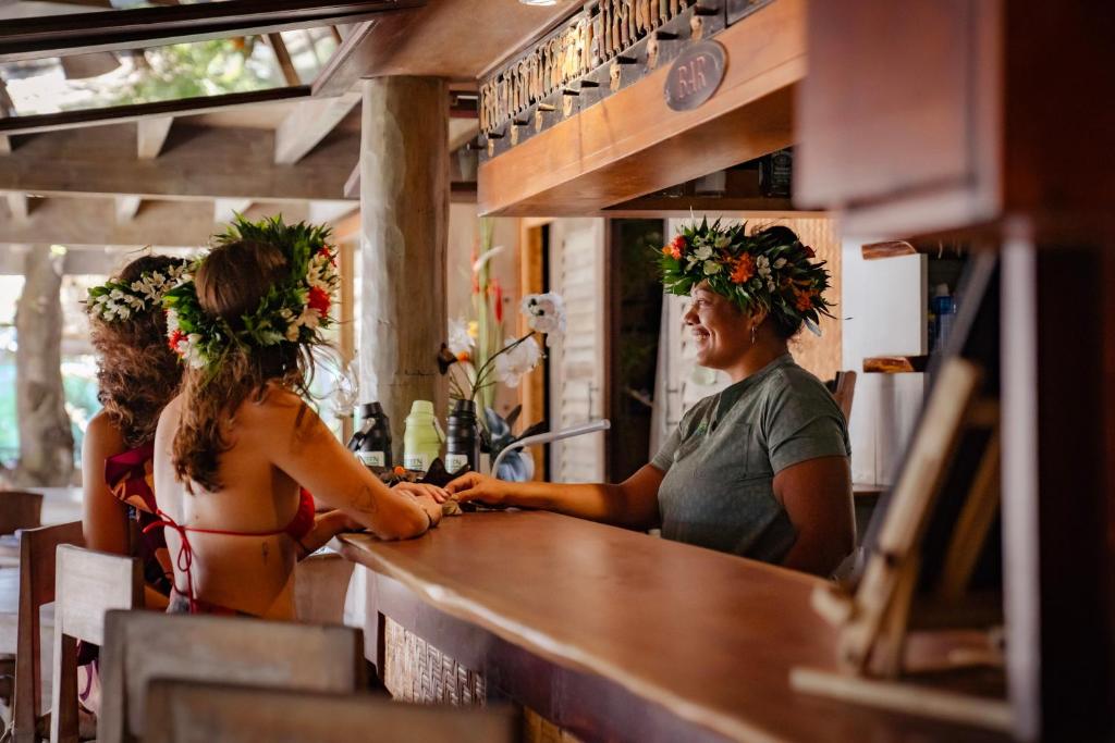 two women sitting at a bar with flower crowns at Green Lodge Moorea in Teavaro