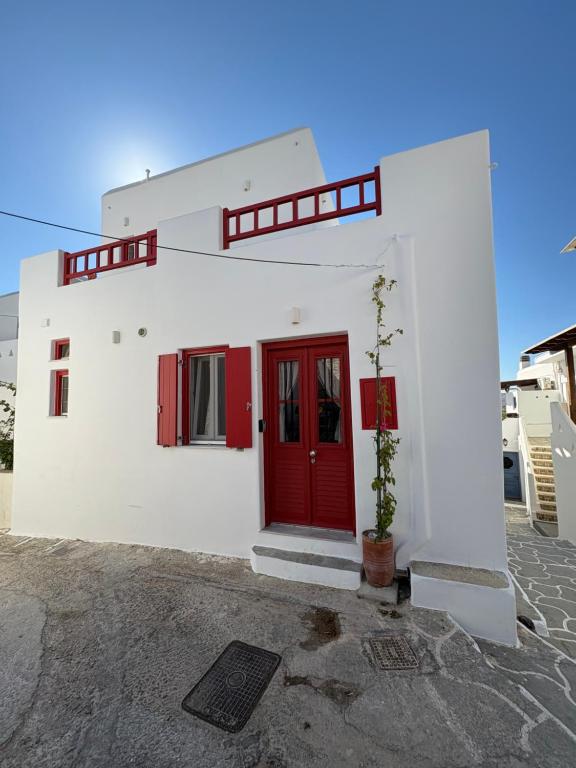 a white building with a red door and a plant at Agioutanti Spot in Kithnos
