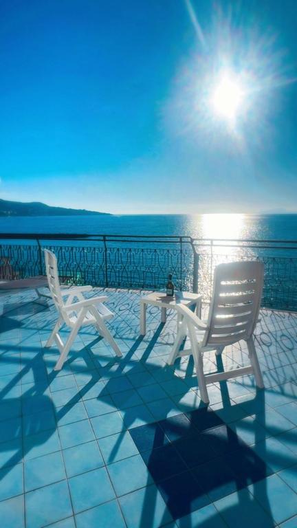 two white chairs and a table on a patio overlooking the ocean at Seaside Dream View-Private Beachfront Terrace in Meta