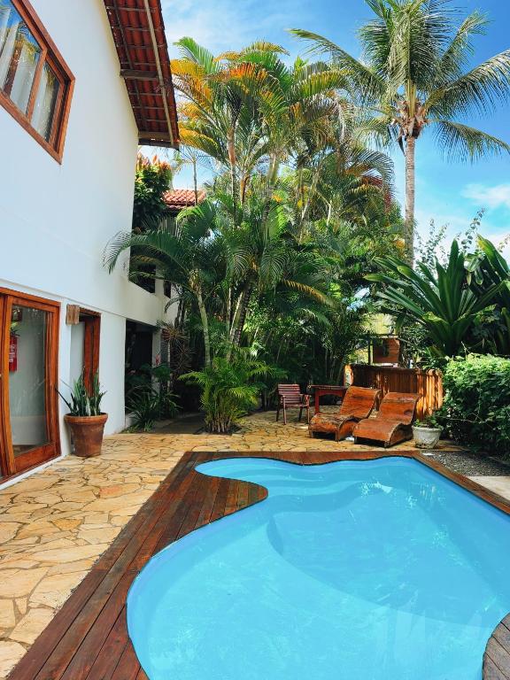 a pool in the backyard of a house with palm trees at Pousada Casa de Inaê in Itacaré