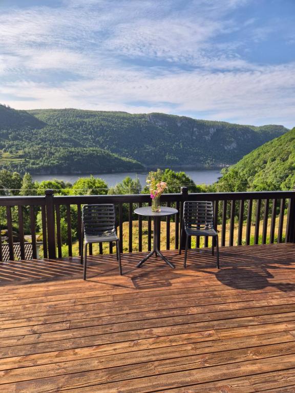 a table and two chairs on a deck with a view at Roligheten hytte in Farsund