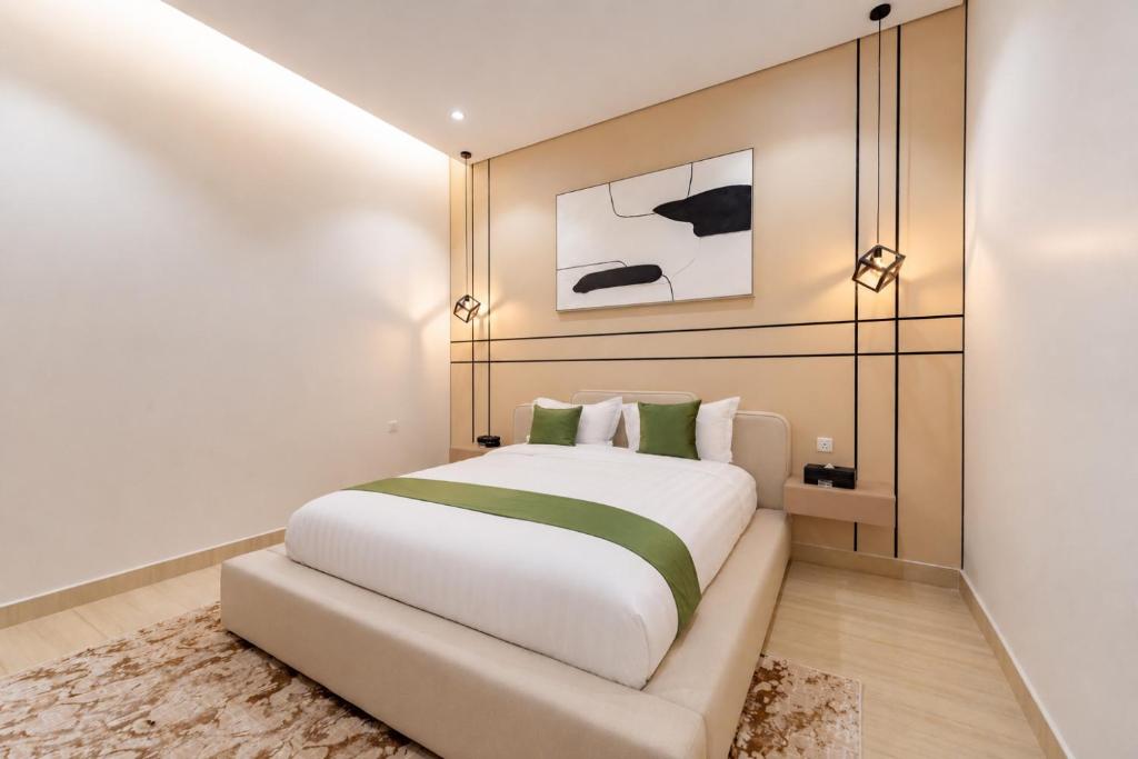 a bedroom with a large white bed with green pillows at السميح للشقق الذاتيه ALsUMAIH HOTELAPARTMENTS in Riyadh