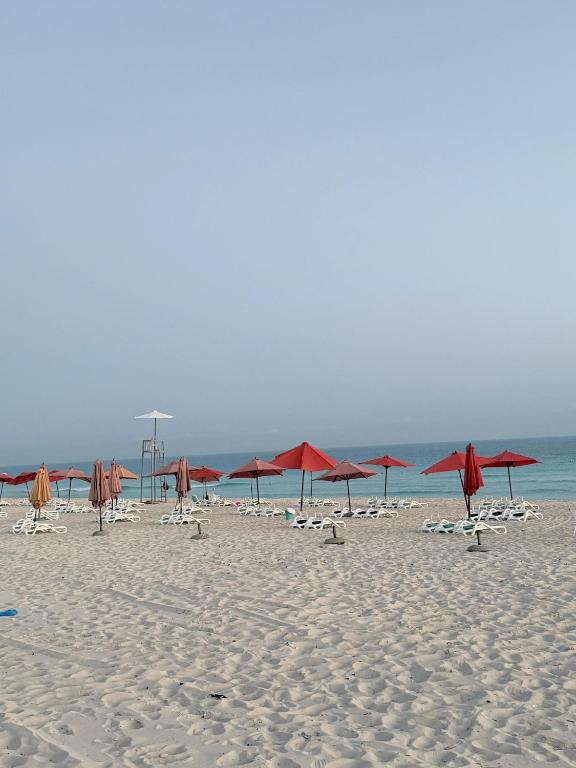 a group of red umbrellas on a beach at Marselia Beach 3 in Dawwār Muḩammad Abū Shanab