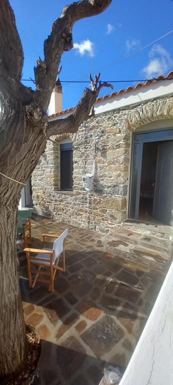 a stone house with a tree and a chair at Vounios house in Manganítis