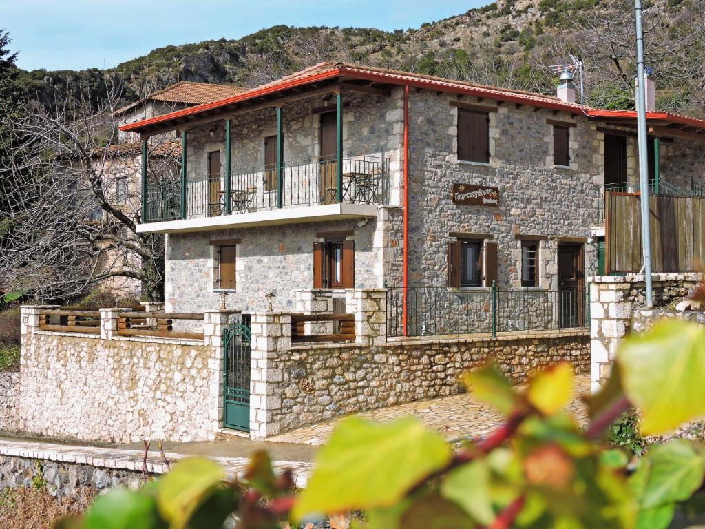 ein Steinhaus mit einem Balkon an einer Steinmauer in der Unterkunft Gartagani Guest House in Stemnitsa