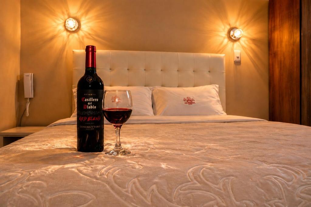 a bottle of wine and a glass on a bed at Hotel Zackenbarsch in Huánuco