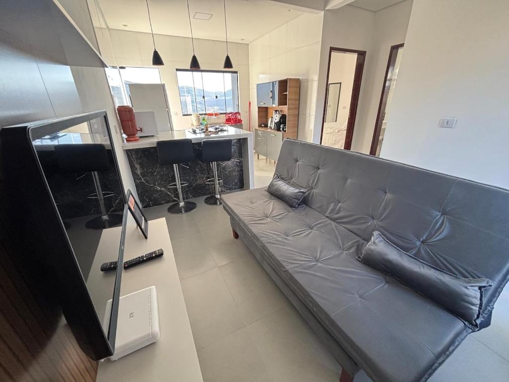 a couch in a living room with a kitchen at Casa completa com wifi, garagem, próximo ao centro in Piatã