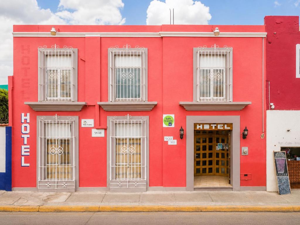 a red building with barred doors on a street at Hotel Posada el Cid in Oaxaca City