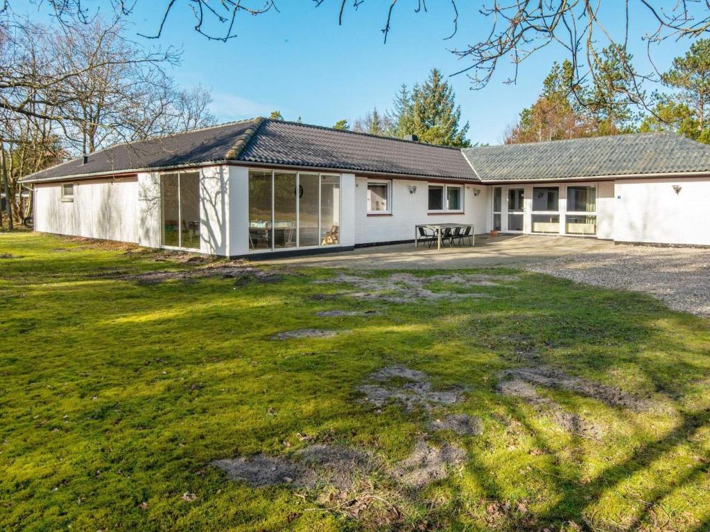 an exterior view of a white house with a large yard at 18 person holiday home in Rømø in Kongsmark