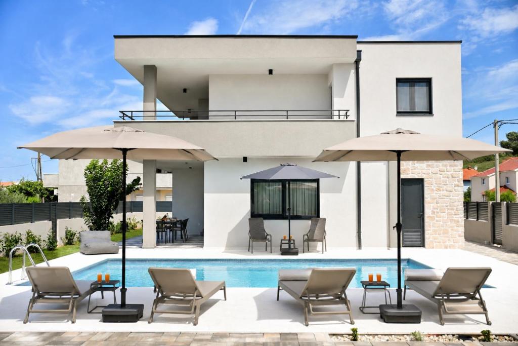 a villa with a swimming pool and umbrellas at Casa Magista in Sukošan