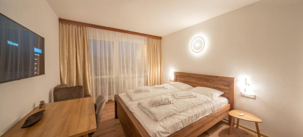 a bedroom with a bed and a desk and a window at Lipno - apartmán C404 in Frymburk