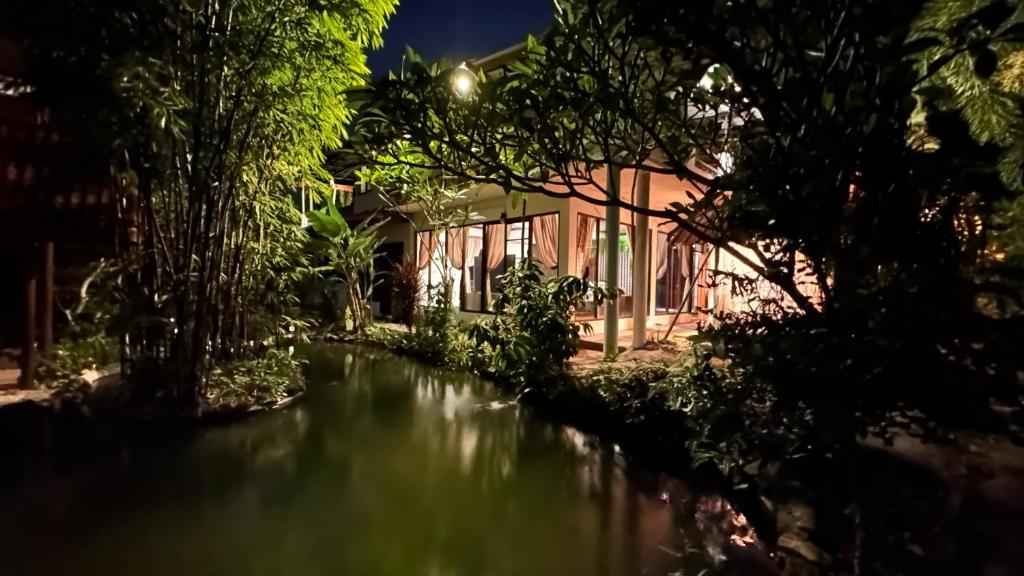 a river in front of a building at night at Nong Thale Garden in Ban Khao Klom