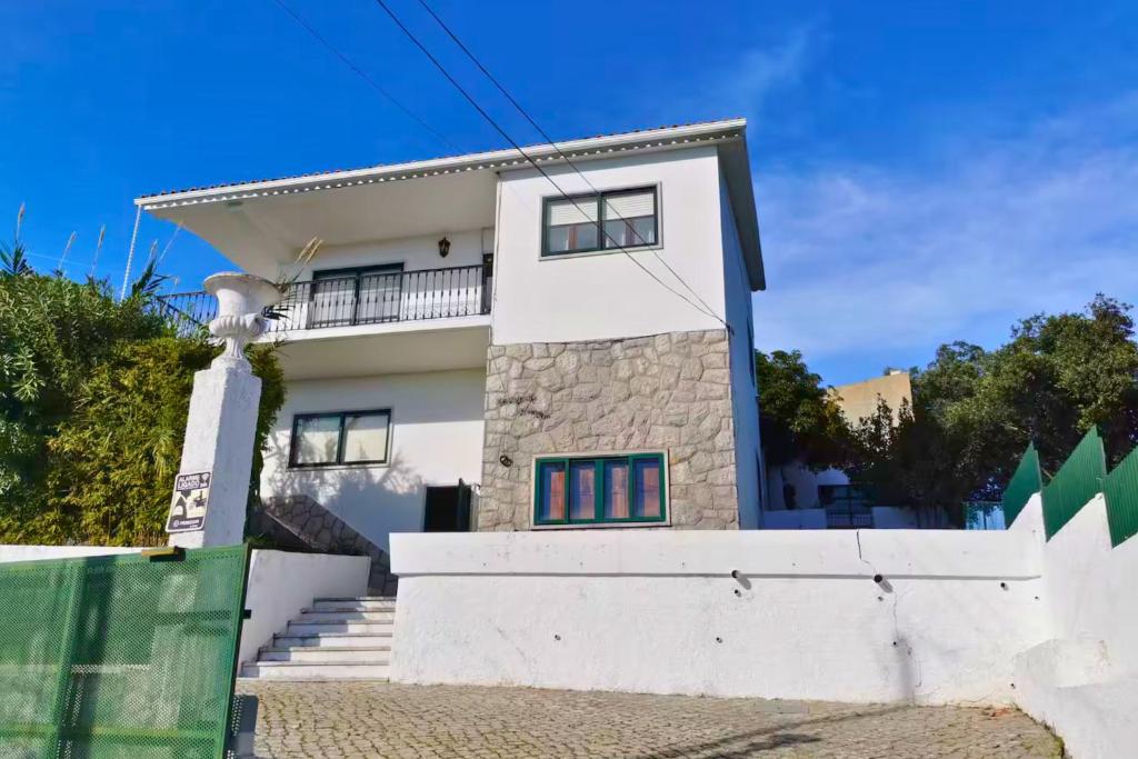 a white house with a fence in front of it at Casa do Castelo - Calm & lovely 2-bedroom Apt Near the Beach in Sesimbra