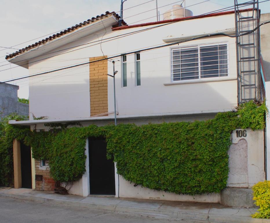 a white house with green ivy growing on it at Luffa Hostel in Santa Lucía