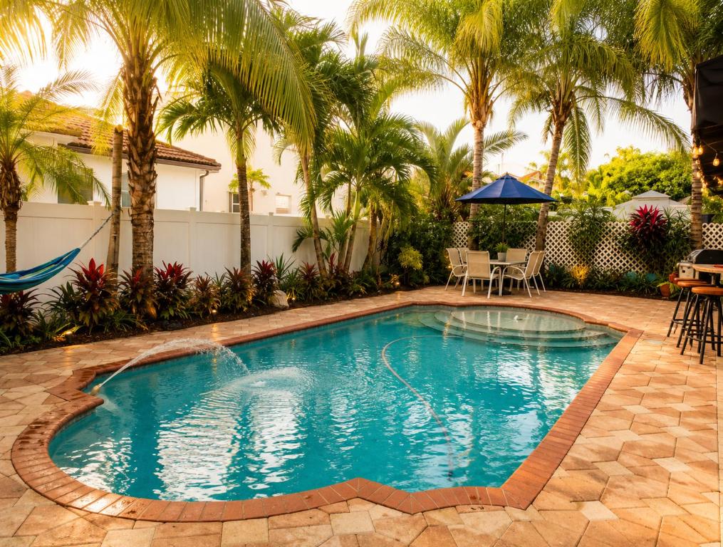 a swimming pool in a yard with palm trees at The Oasis, Miami Lakes in Miami Lakes