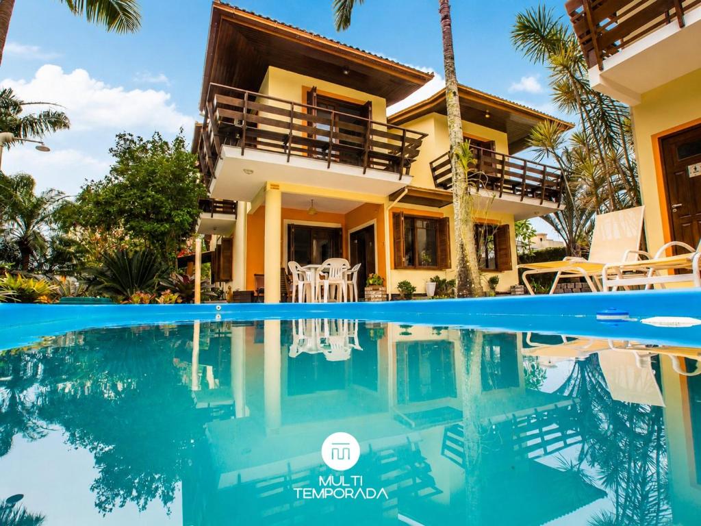 a villa with a swimming pool in front of a house at Bollté Praia Boutique Pousada - Campeche - Floripa - SC in Florianópolis