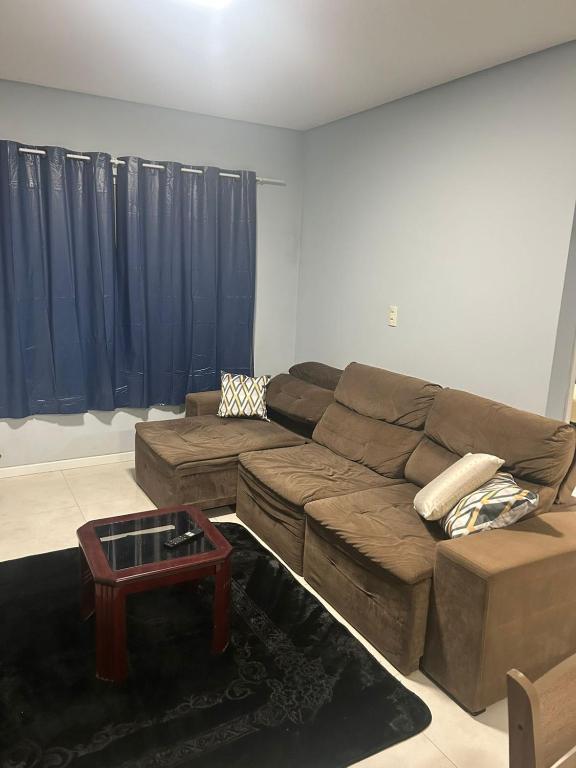 a living room with a brown couch and a table at Casa completa bem equipada ótima localização in Joinville
