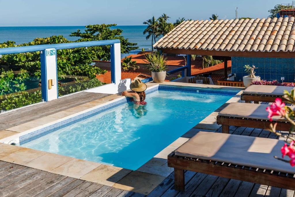 a woman in a swimming pool next to the ocean at Vila Maria Pousada in Jericoacoara