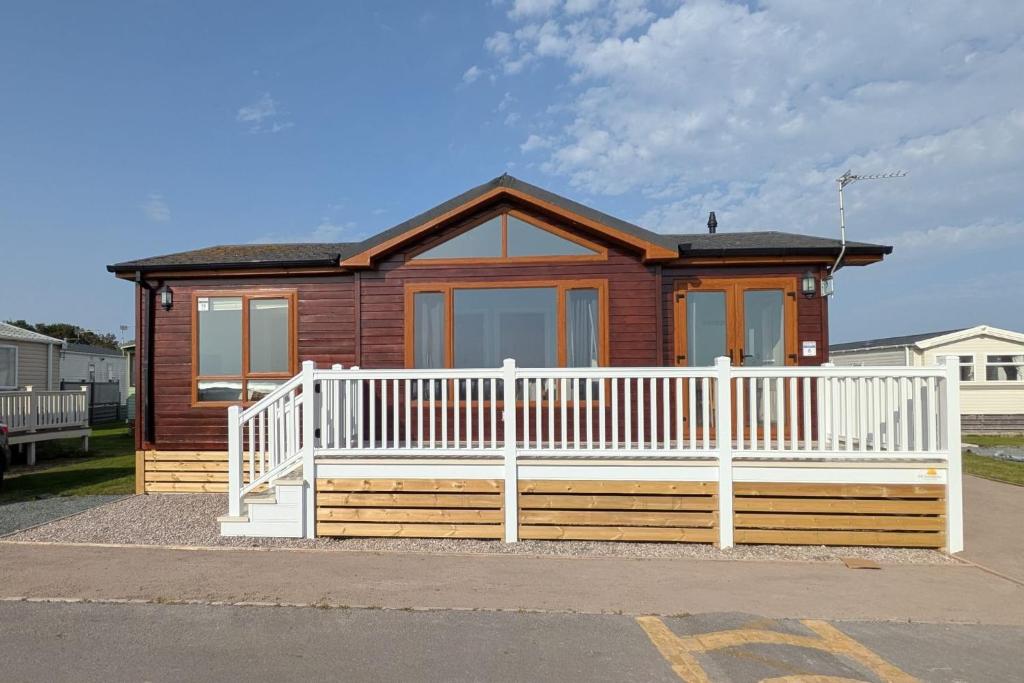 a small house with a white fence in front of it at Sea View Retreat Lodge in Heysham