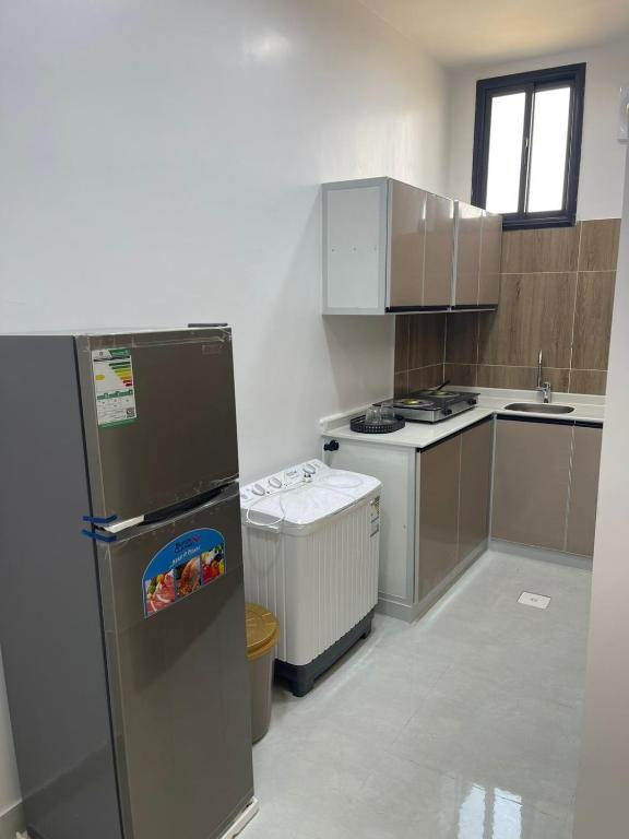a small kitchen with a refrigerator and a sink at سويتات توت in Al Mikhlaf