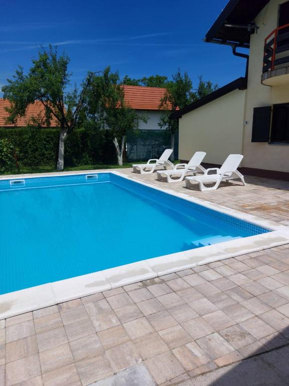 a blue swimming pool with chairs and a house at Villa Valinor in Slatina Varoš