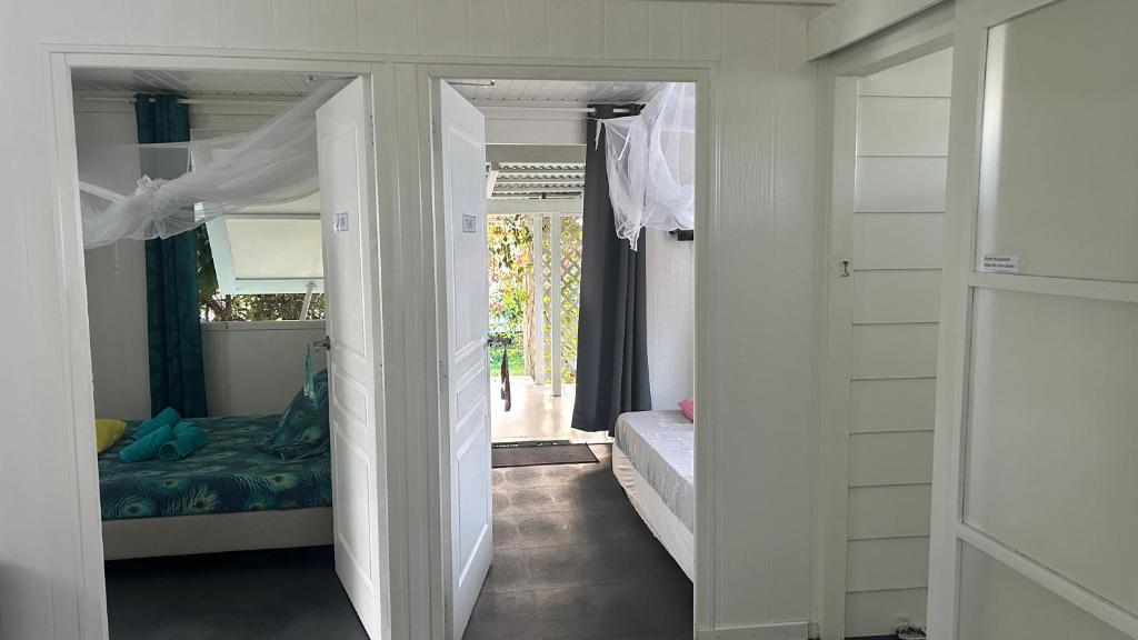 a room with a bedroom with a bed and an open door at LE FARE BLEU DUO 2 chambres climatisées avec 1 salle de bain - bord de lagon à Tiputa Rangiroa - vélos gratuits et snorkeling in Rangiroa