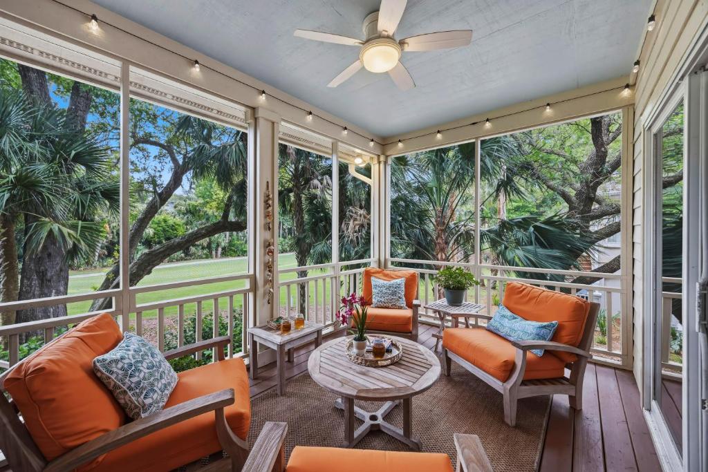 a screened porch with orange chairs and a table at OG23: 23 Ocean Green in Kiawah Island