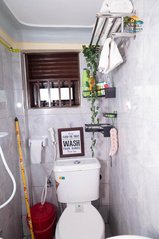 a bathroom with a toilet with a sign on it at Shan in Jinja