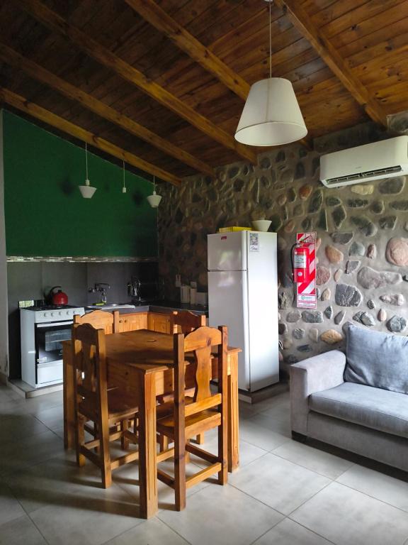 a kitchen with a wooden table and a refrigerator at Cabañas 2TIERRAS in Chicoana