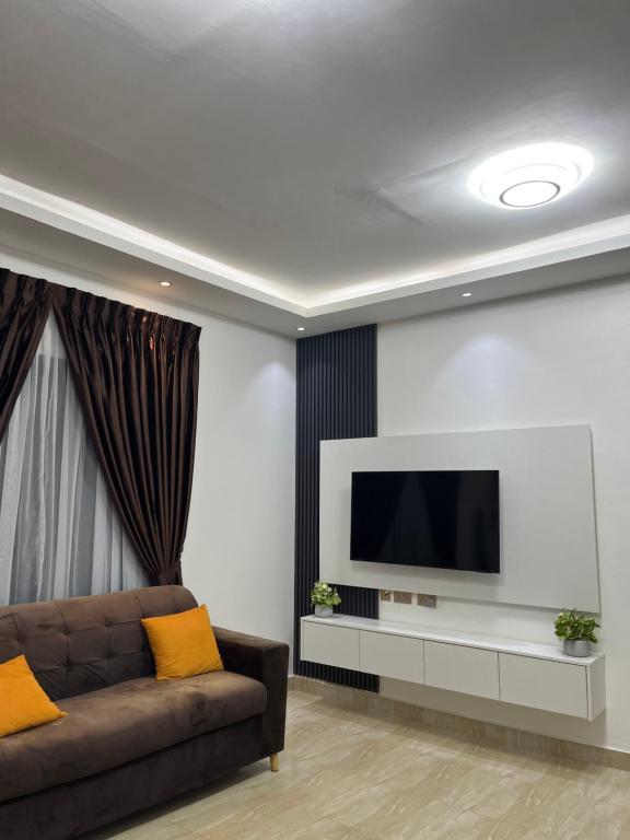 a living room with a couch and a flat screen tv at Serene Coastal Escapes GH in Prampram