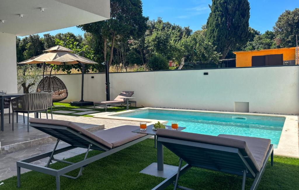a swimming pool with two chairs and a table next to it at Lovely Apartment In Rovinj in Rovinj