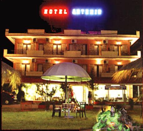 a building with a table and an umbrella in front of it at Artemis in Paralia Katerinis