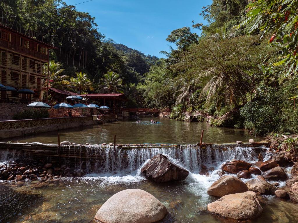 a waterfall in a river with people swimming in it at Hotel Termales Espiritu Santo in Nariño