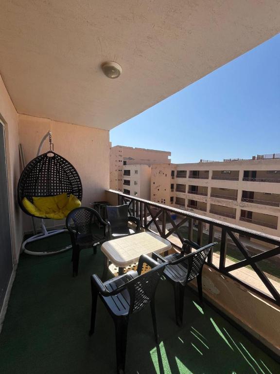 a balcony with chairs and a table and a swing at شالية غرفتين بقرية ديمورا in Dawwār Muḩammad Abū Shunaynah