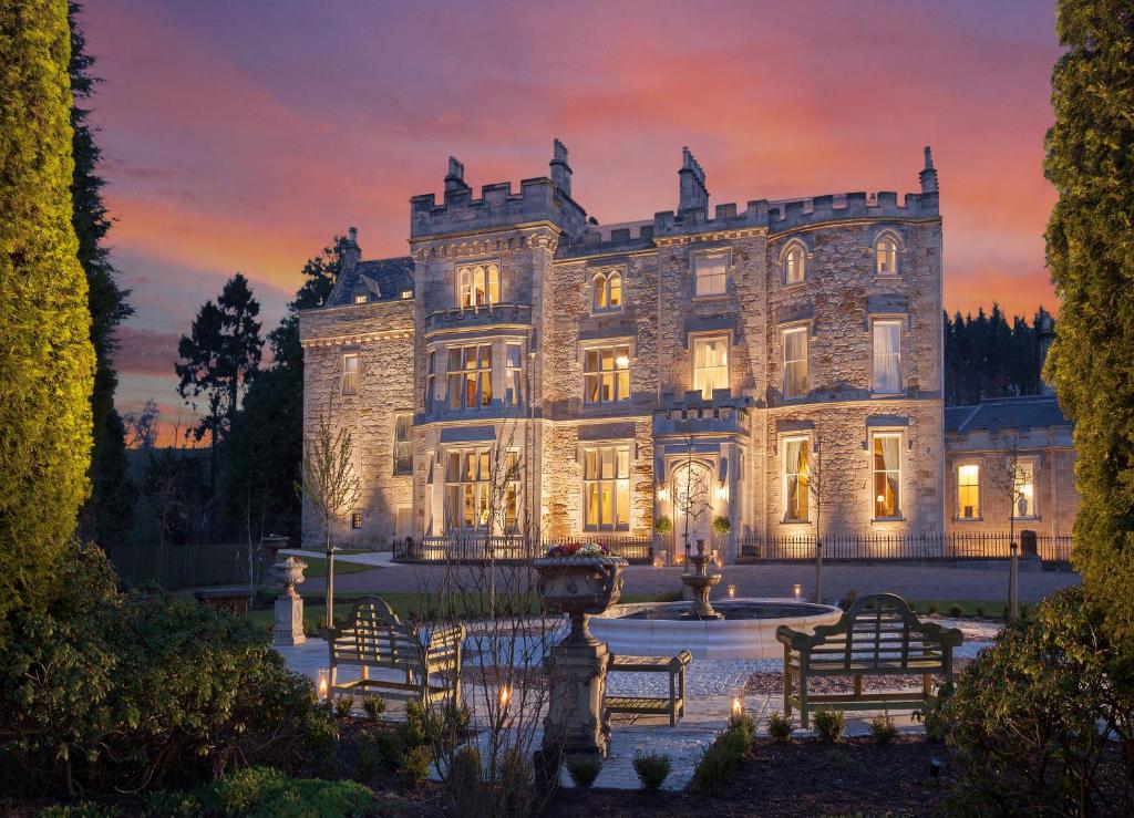 an old stone house with a fountain in front of it at Crossbasket Castle in High Blantyre