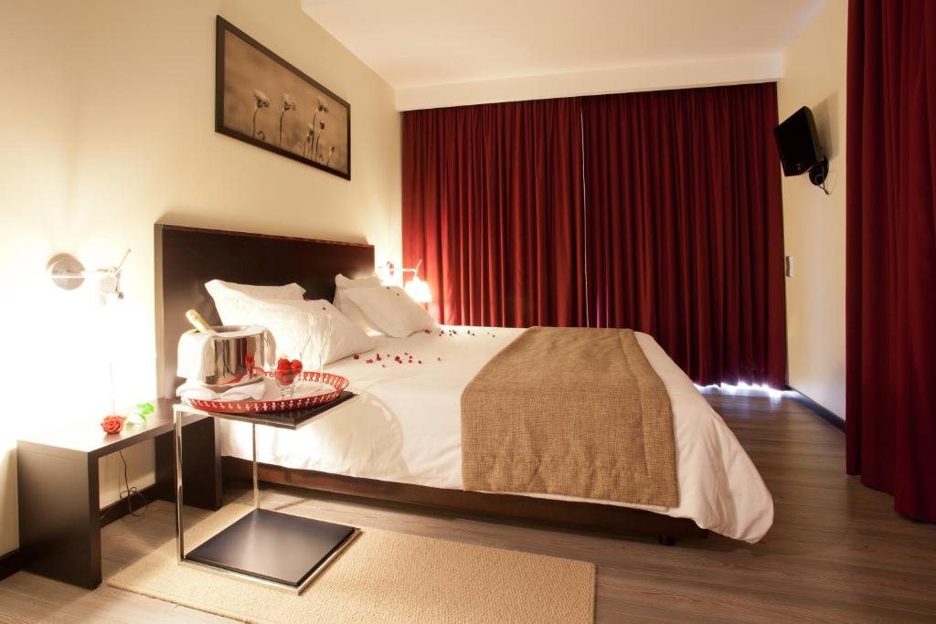 um quarto com uma cama grande e cortinas vermelhas em Hotel Sao Pedro em Arouca