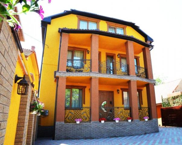 uma casa amarela com uma varanda em cima em Goldenluxe em Berehove