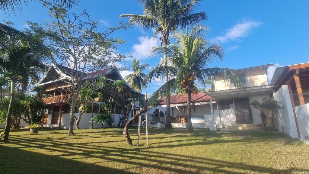 a house with palm trees in front of it at Rumah Mana Beach House in Pulau Sarang