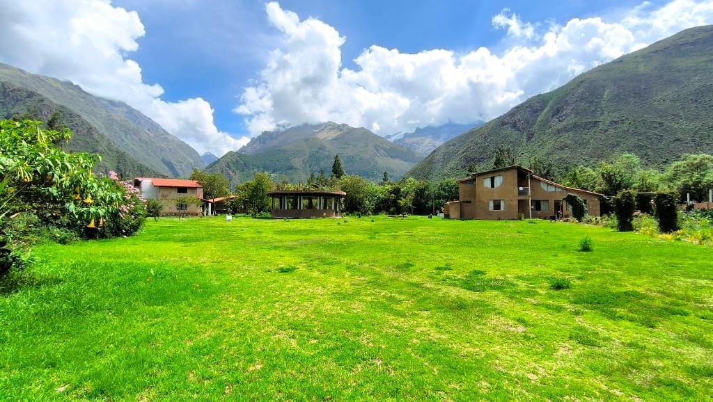 a green field with houses and mountains in the background at Tikary Lodge in Cusco