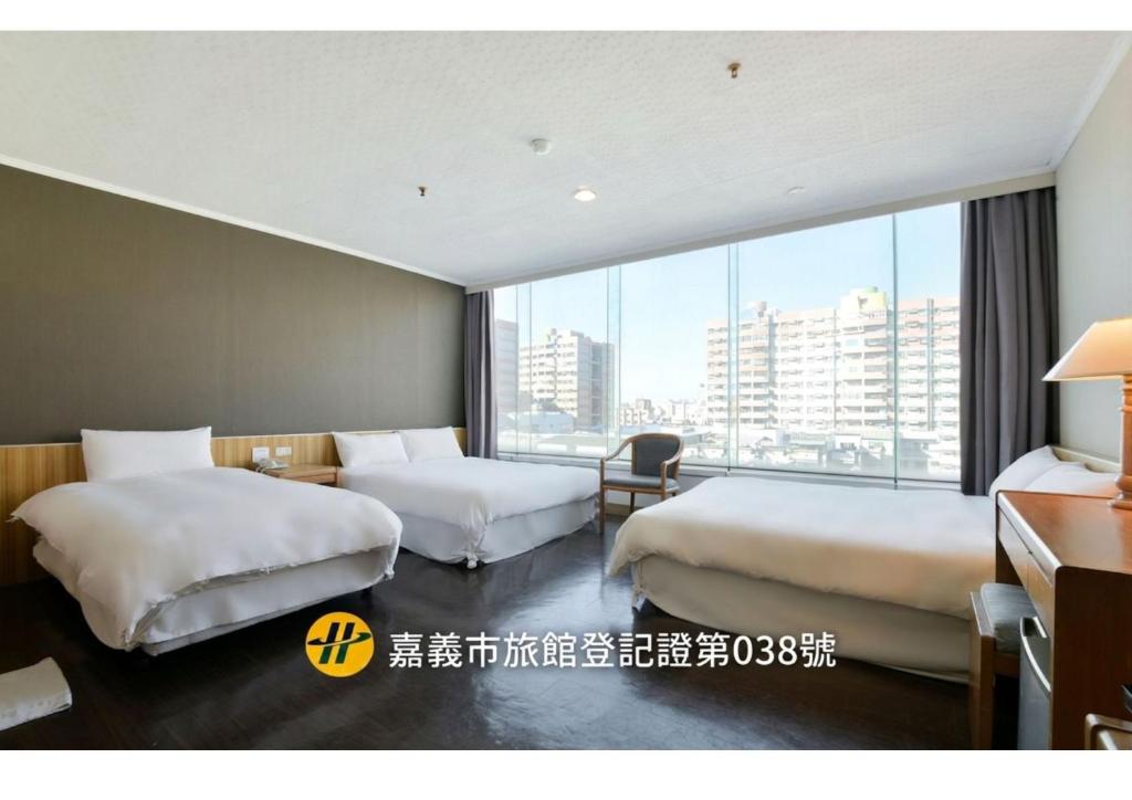 ein Hotelzimmer mit zwei Betten und einem großen Fenster in der Unterkunft Back Home Hotel in Chiayi