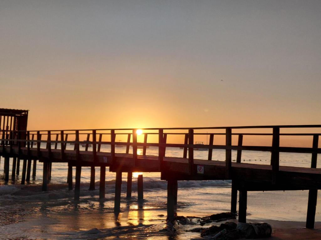 a pier with the sun setting on the ocean at Coral Beach Hotel Punta Cana in Punta Cana