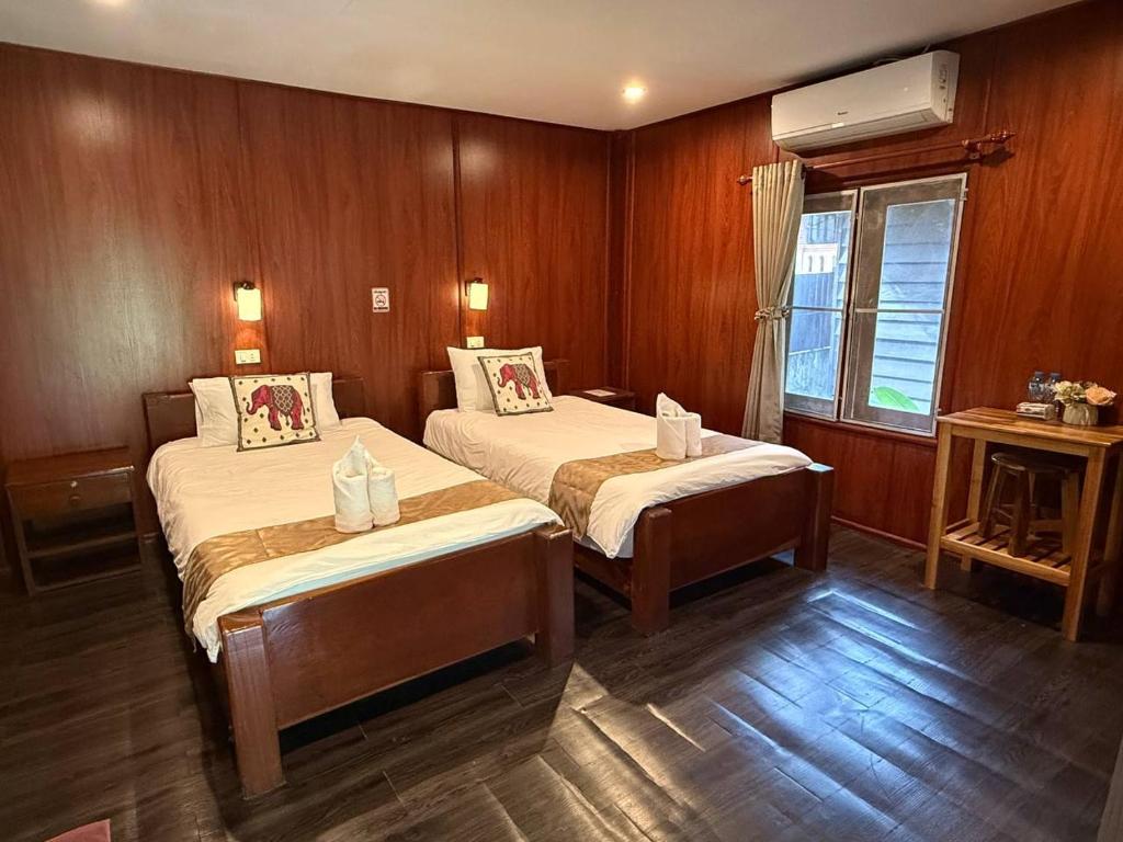 a room with two beds and a window in it at D-Chu Mountain Haven Villas in Vang Vieng