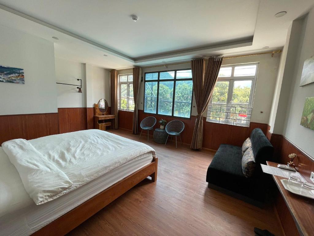 a bedroom with a bed and a couch and windows at Flaco Hostel and Booking Office in Sapa