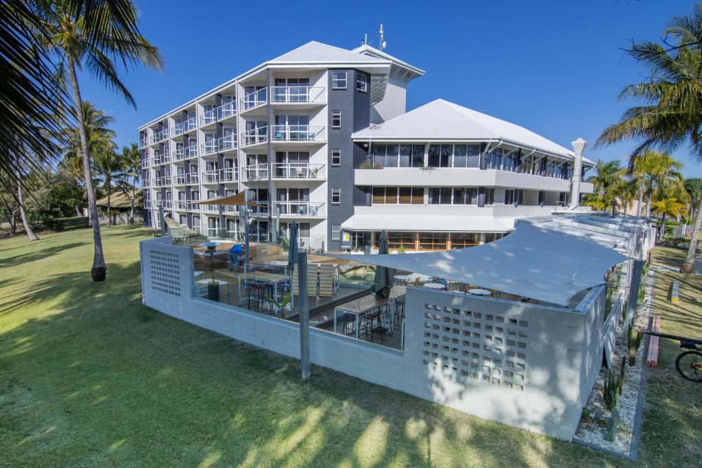 a large white building with palm trees in front of it at Ocean International Hotel in Mackay