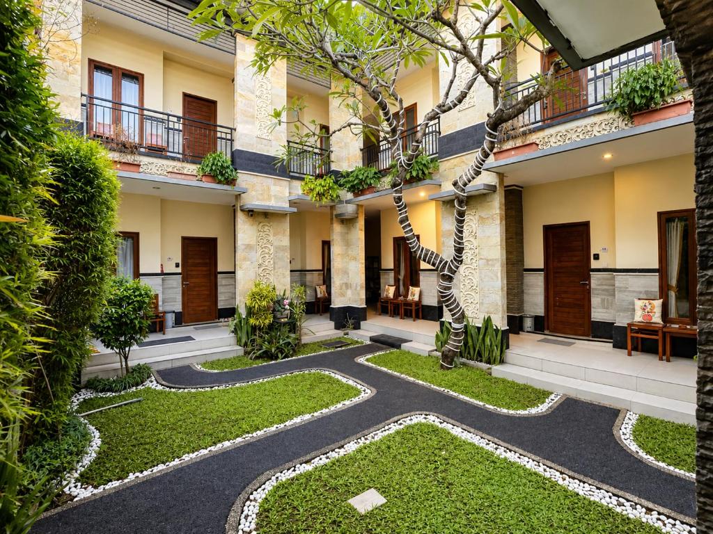 an internal courtyard of a building with a tree at Eslem GuestHouse in Canggu