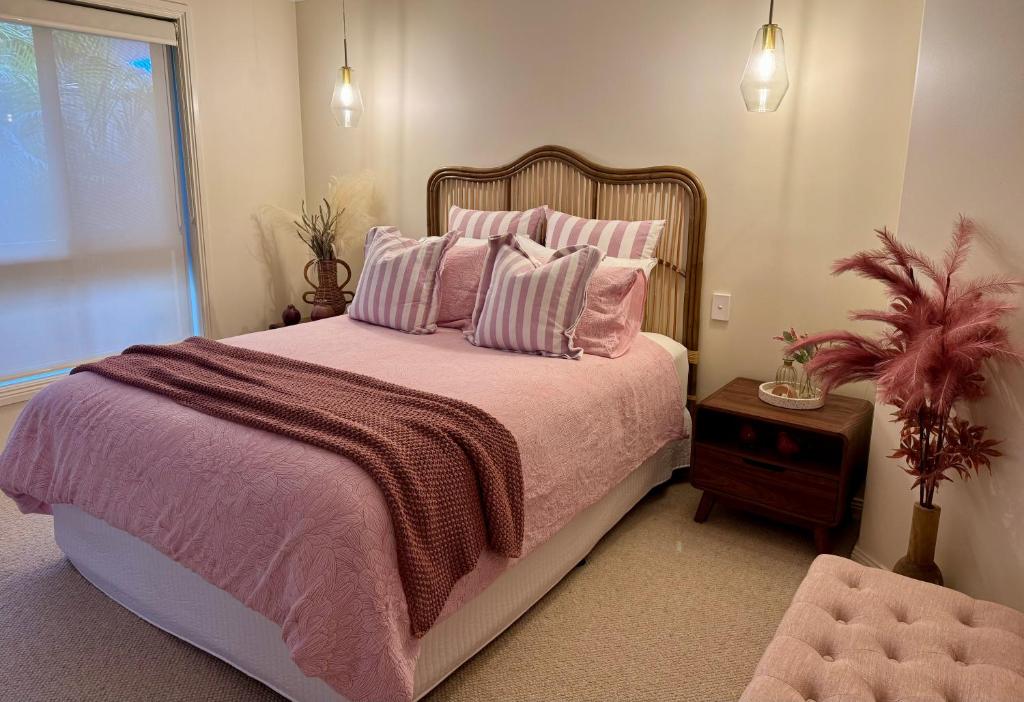a bedroom with a large bed with pink sheets and pillows at Budgaribah in Old Bar