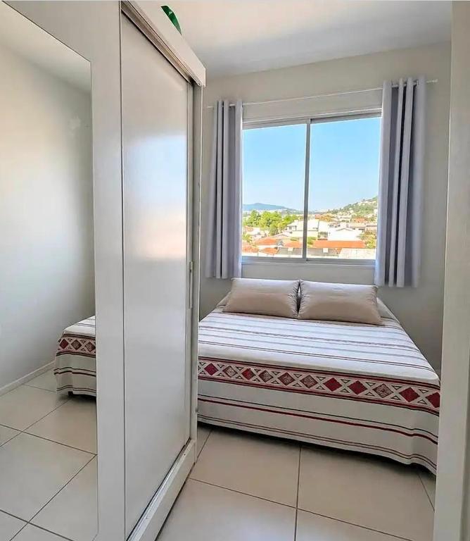a bed in a room with a window at Quarto Aconchegante em Residência Familiar in São José