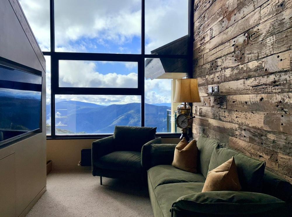 a living room with a couch and a large window at Mt Buller Chalet Hotel & Suites in Mount Buller